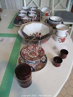 Full view of table display showing the oriental bowls, tiered plate, cups, and tray, capturing the full lot contents.