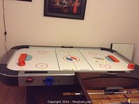 Full view of the Sportscraft Turbo air hockey table with playing surface, orange paddles, and table edges visible