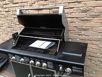 Grill open showing dual-level cooking grates and control panel with five stainless steel knobs