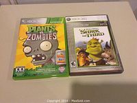 Photo shows Plants vs. Zombies and Shrek the Third Xbox 360 game cases placed side by side on a flat surface.