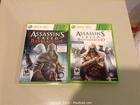 Assassin's Creed Revelations and Assassin's Creed Brotherhood Xbox 360 game cases displayed side by side