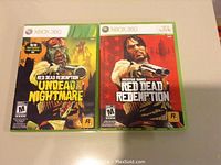 Two Xbox 360 game cases showing Red Dead Redemption Undead Nightmare and Red Dead Redemption games.
