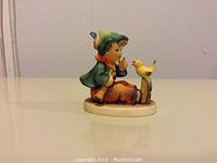 View of the figurine from the front showing the boy seated next to the bird on a stump, detailed hand-painted colors and facial expression visible.