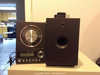 Photo showing TEAC micro Hi-Fi CD player main unit with large round silver volume dial and an attached single speaker subwoofer unit next to it.