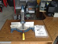 Top-down view of base and blade of Mastercraft power miter saw showing angle adjustment scale and saw blade.