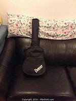 Soft black carrying case with Denver logo placed on a brown leather couch.