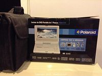 Box and carrying case for Polaroid portable DVD player with printed image of the player and list of included accessories.