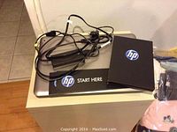 Closed laptop with AC adapter, power brick, cable and HP setup booklets