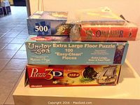 Stack of three puzzle boxes: 500-piece puzzle, 100-piece extra large 'Under The Sea' puzzle by Melissa & Doug, and 358-piece 3D pirate ship puzzle by Wrebbit.