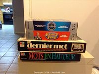 Stack of Family Feud DVD, Who Wants to Be a Millionaire DVD, Dernier Mot board game, and Mots en Hauteur board game boxes, showing title labels and packaging condition.