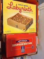 Photo of Labyrinth solid wood maze game box on top and Balderdash board game box below it showing product branding.