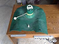 Overview of the MasterSwing putting green showing the putting surface, ball return, and swing analyzer device mounted centrally.