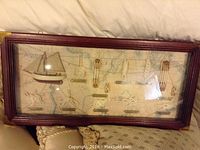 Full view of the framed nautical art showing model sailboat and display of different real knots mounted on a chart background.