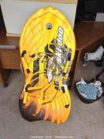 Yellow and black Ski-Doo snow sled with molded seating, branded design, and handles.