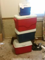 Stack of four medium to large coolers in red, blue, and white, with a small white cooler on top.