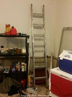 Full view of the twelve foot adjustable metal extension ladder standing upright among other household items.