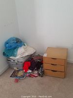 Wide shot showing fabric and craft supplies on floor and wooden drawer unit