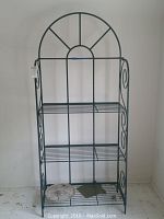 Front view of the green metal bakers rack showing four wire shelves and arched top design.