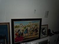 Photo showing Spanish-themed painting, part of Ray Charles print, and shadows indicating other framed artwork