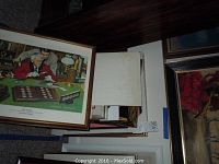 Framed print partially visible among stacked frames