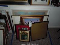 Pile of prints and frames of various sizes leaning against a wall.