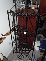 Photo showing one of the metal corner racks angled to show the curved scroll decorative design on the sides and top.