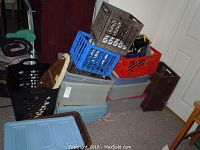 Multiple plastic storage tubs stacked alongside several plastic milk crates in various colors including black, red, blue, and brown.