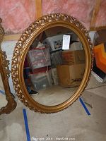 Full view of oval mirror showing gold-colored ornate plastic frame and size relative to surroundings