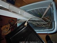 Photo showing a blue laundry basket with various tools including a hand saw, power strip, and electrical cords