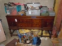 Wide view of wooden cabinet with several toolboxes, tools, cables, and a power saw.