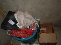 Collection of fabric pieces including a plaid pattern and light-colored fabric in bins with a box of books beside it.