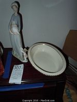 Photo showing both Lladro figurine with broken piece and Lenox Citation Gold bowl on a wooden surface.