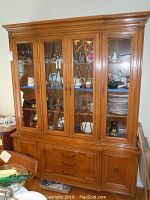 Full view of Thomasville china cabinet showing wood finish, glass front doors with metal design, lower drawers, and cabinet doors.