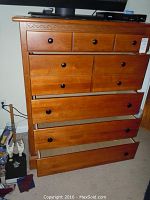 Front view showing six drawers, carved detail on top front, black knobs, and visible surface wear.