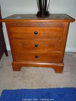 Front view of one Vaughan wooden side table with three drawers and black knobs, showing carved detail above drawers.