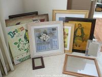 Group photo showing multiple framed art pieces, cork board, and small decorative frames arranged against a wall.