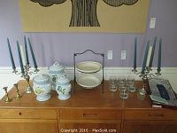 Wide view of all items including candelabras, candlesticks, ceramic canisters, plates, glasses and serving tray.