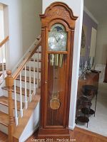 Full front view of clock case, glass door, brass weights and pendulum