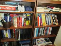 Bookshelves full of textbooks, reference books, Dummies self-help books, organizers and other paperbacks in various sizes and condition.