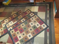 Three rugs displayed together with part of the large rug and three smaller runners stacked