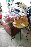 Overall lot with stacked folding outdoor chairs, wicker storage bin, stacking side tables, and terra cotta planters on the side table.