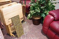 Folding snack tables stacked beside fireplace tools and artificial plant on carpet