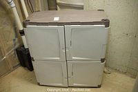 Front view of the Rubbermaid storage unit with four closed doors, showing the tan top and beige door panels with brown trim.