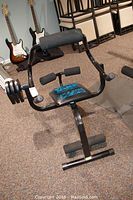 Full view of the Body By Jake AB & Back Plus exercise machine showing padded seat and backrest, foam rollers, and weight plates attached.