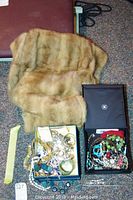 Autumn Haze mink stole laid on carpet with two boxes containing assorted costume jewelry including bracelets, necklaces, and watches