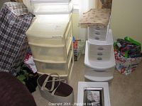 Overall view showing multiple plastic stackable drawer units and colorful bags around them.