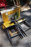 Three black wooden director chairs; one new in box with black canvas, two used with yellow canvas, showing folded chairs and box.