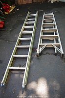 Two aluminum ladders laid out on outdoor pavement, showing side rails and rungs. One is longer (10ft extension ladder), the other shorter (6ft step ladder).