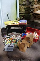 Wide shot showing work bench, manuals, toolbox, and assortment of tools spread out on ground