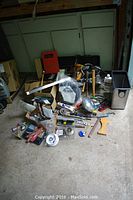 Photo showing a variety of tools including hand tools, a trash bin, and small hardware items scattered on the floor.